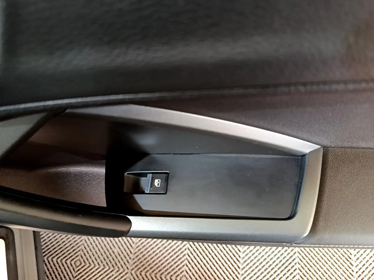 Gros plan sur le bouton de verrouillage centralisé dans la porte côté conducteur de l'Audi Q3 gris foncé 35 TFSI S line.