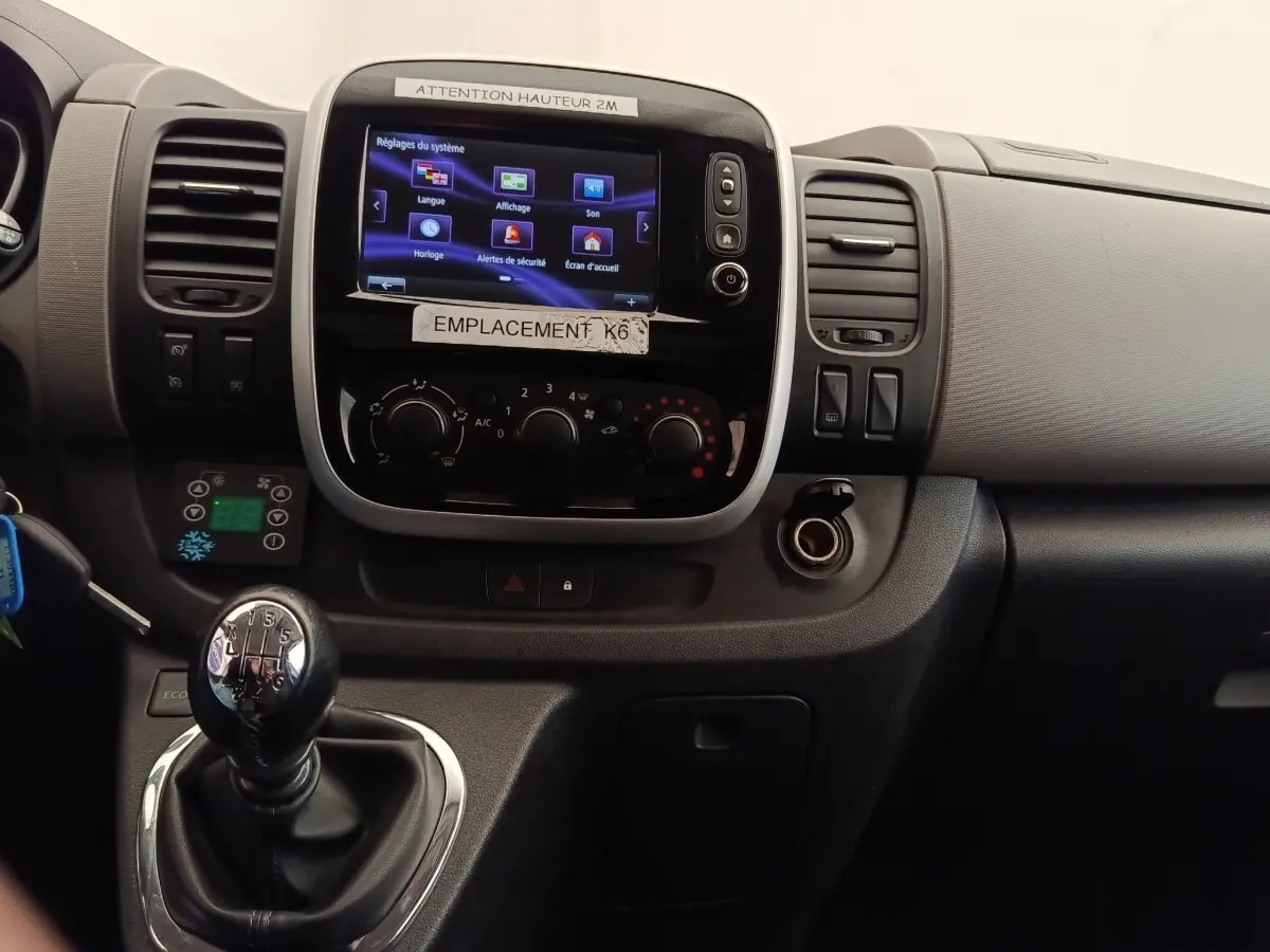 Vue rapprochée du tableau de bord noir du Renault Trafic Fourgon 2017 avec écran tactile et levier de vitesse manuel.