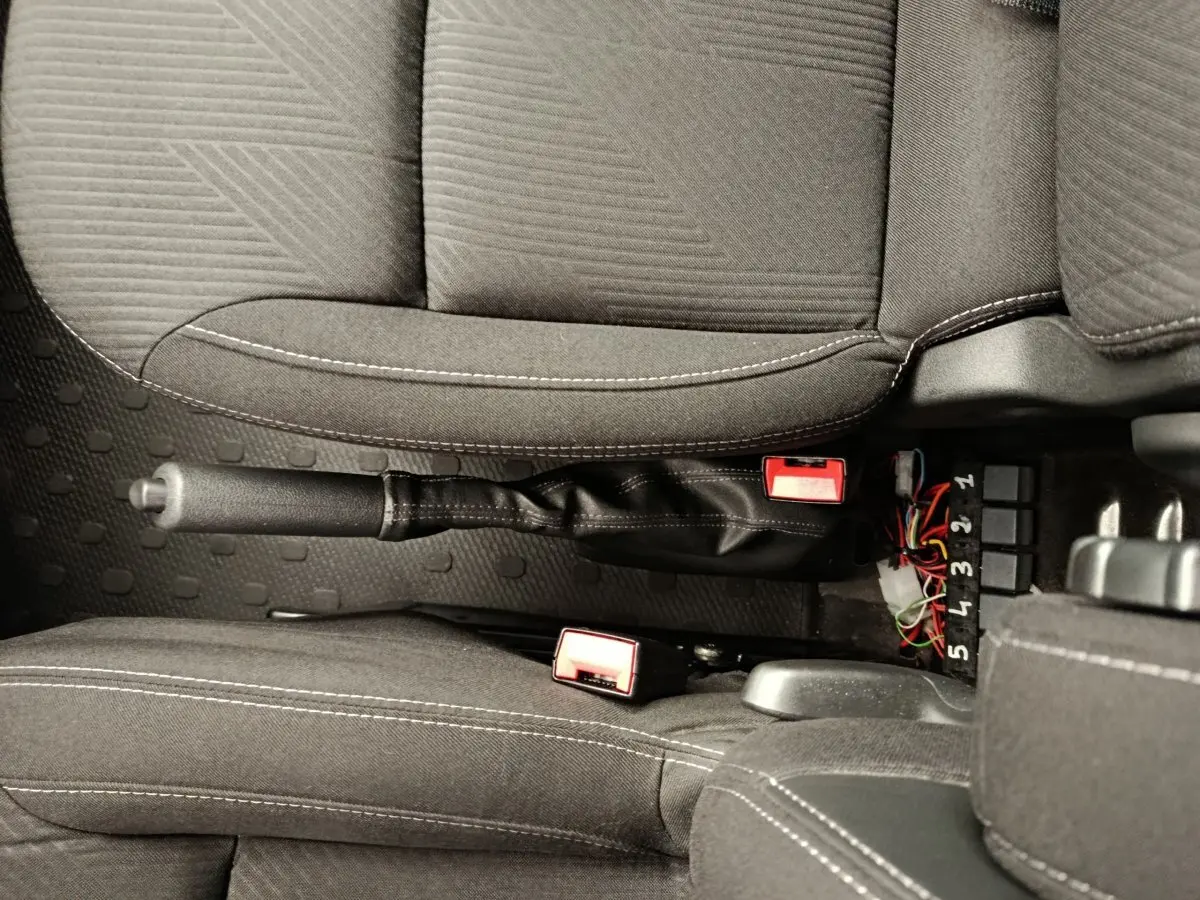 Vue rapprochée de l'intérieur du Renault Trafic Fourgon 2017, montrant la console centrale avec frein à main et ceintures noires.