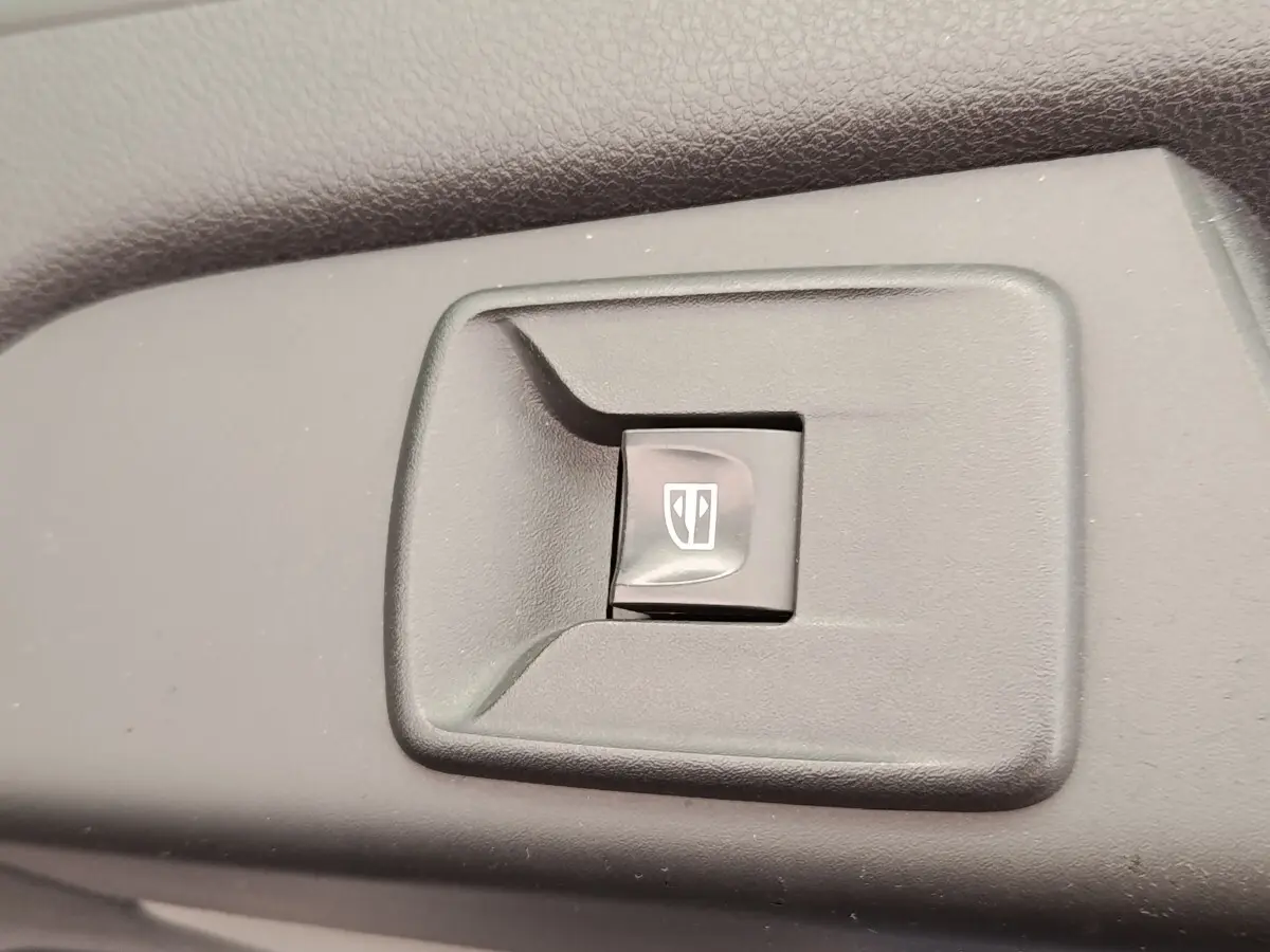 Gros plan sur l'interrupteur de lève-vitre électrique dans l'habitacle du Renault Trafic Fourgon blanc.