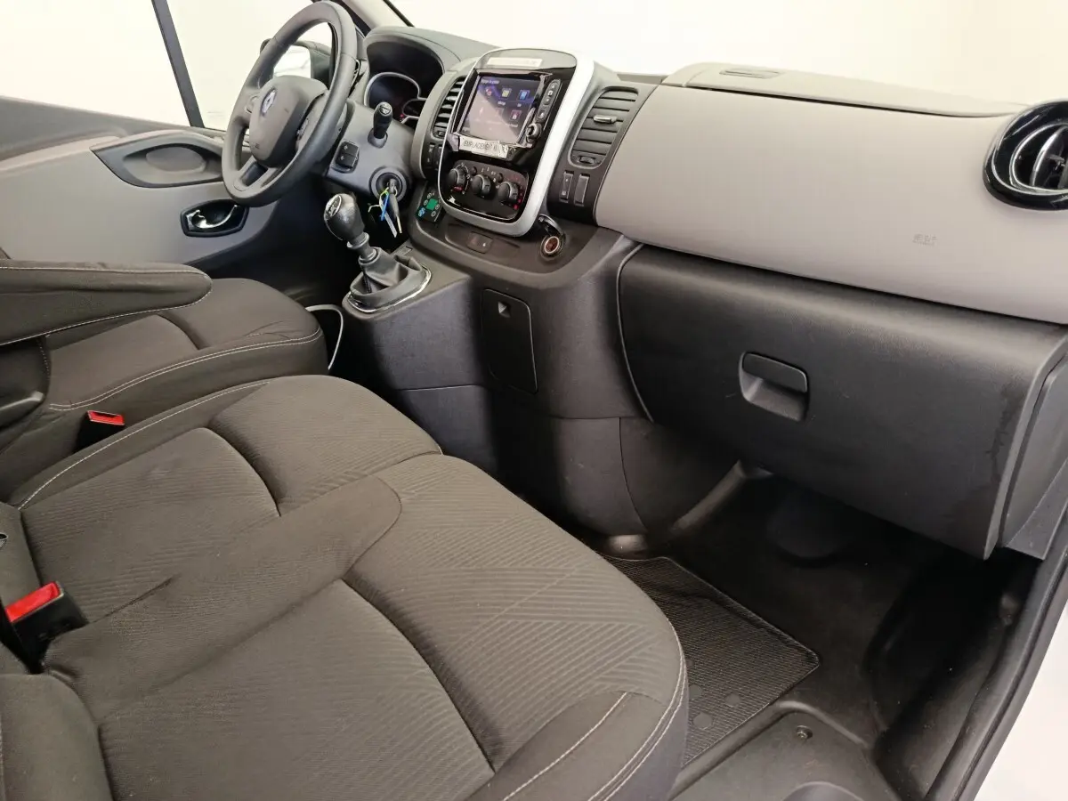 Vue intérieure côté passager du Renault Trafic Fourgon 2017, montrant sièges noirs et tableau de bord clair avec console centrale.