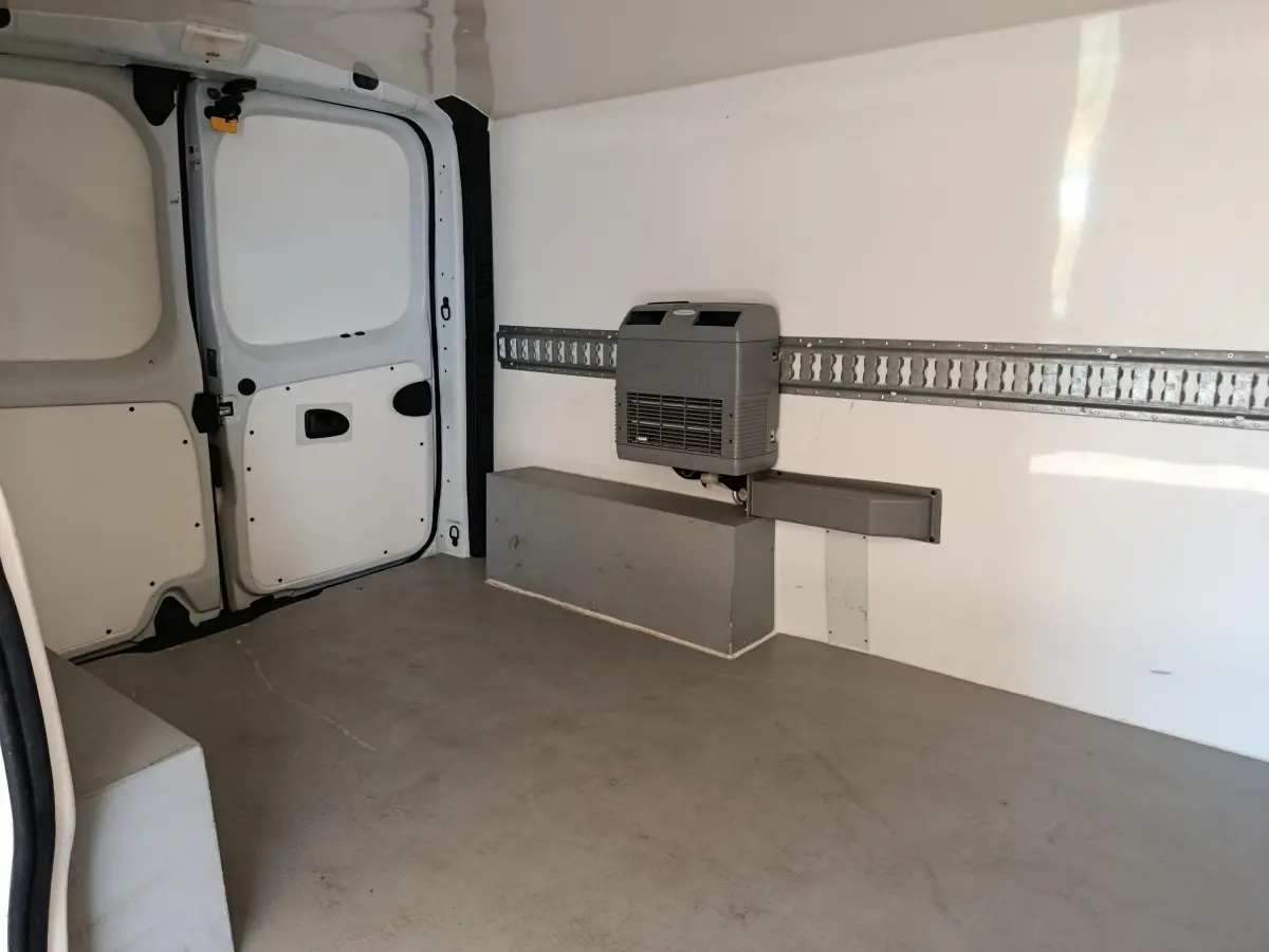 Intérieur du fourgon Renault Trafic blanc, vue arrière droite montrant l'espace de chargement vide avec cloison pleine.