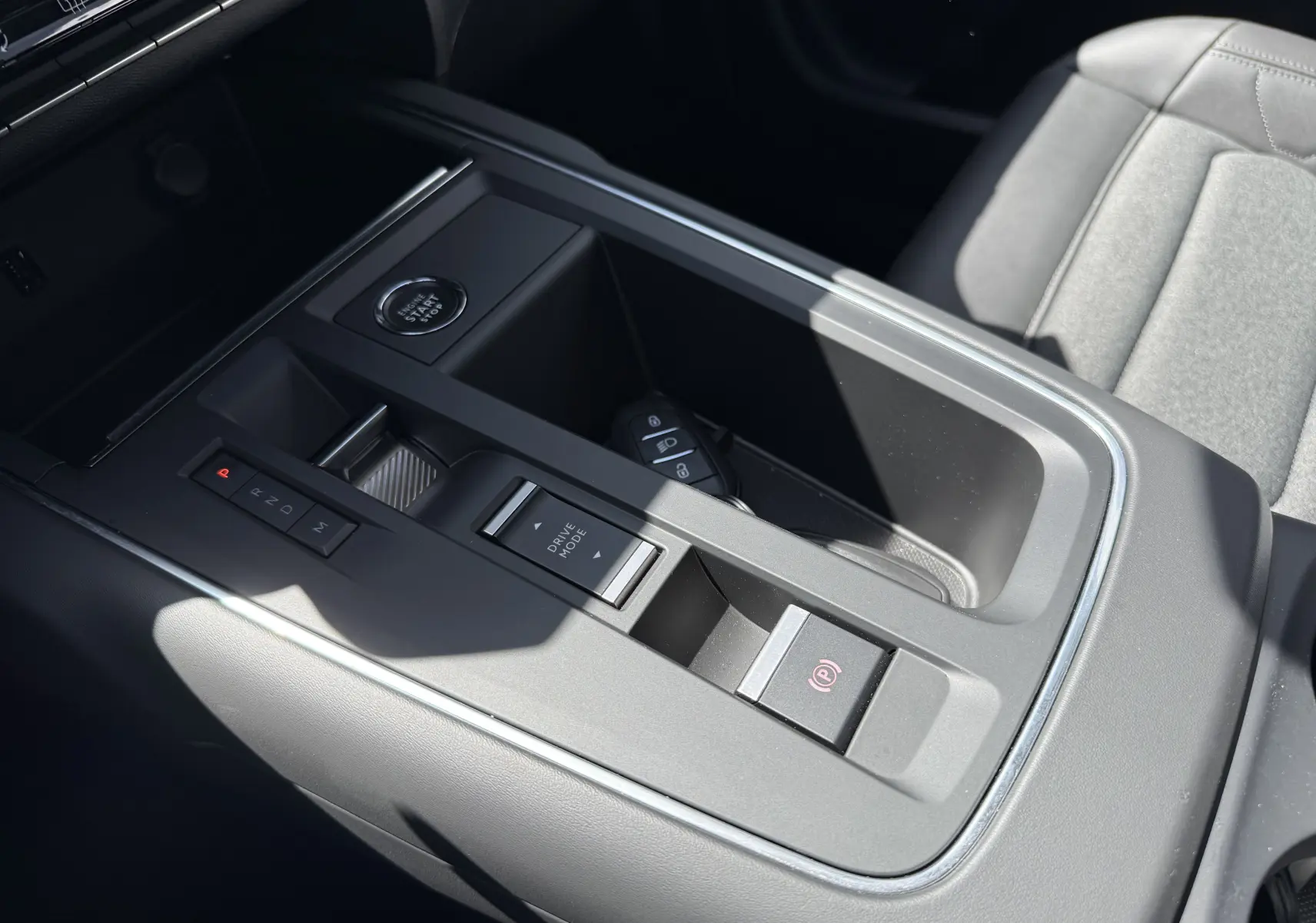 Vue rapprochée de la console centrale grise du Citroën C5 Aircross Hybrid 2025 avec bouton start/stop et commandes de boîte auto.