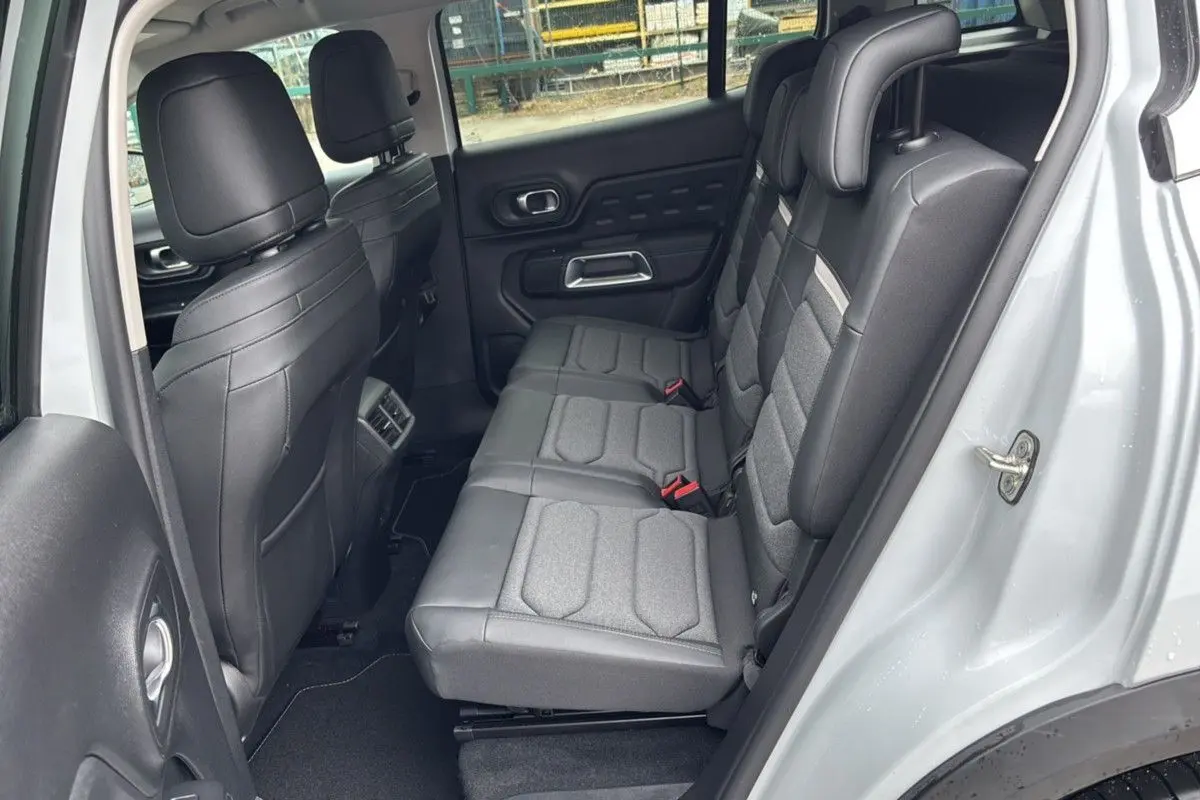 Vue latérale arrière montrant l’intérieur noir et gris du Citroën C5 Aircross Hybrid 2025 avec portes ouvertes.