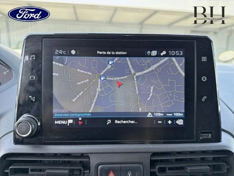 Écran tactile central affichant la navigation d'un Peugeot Partner blanc, vue intérieure du tableau de bord.