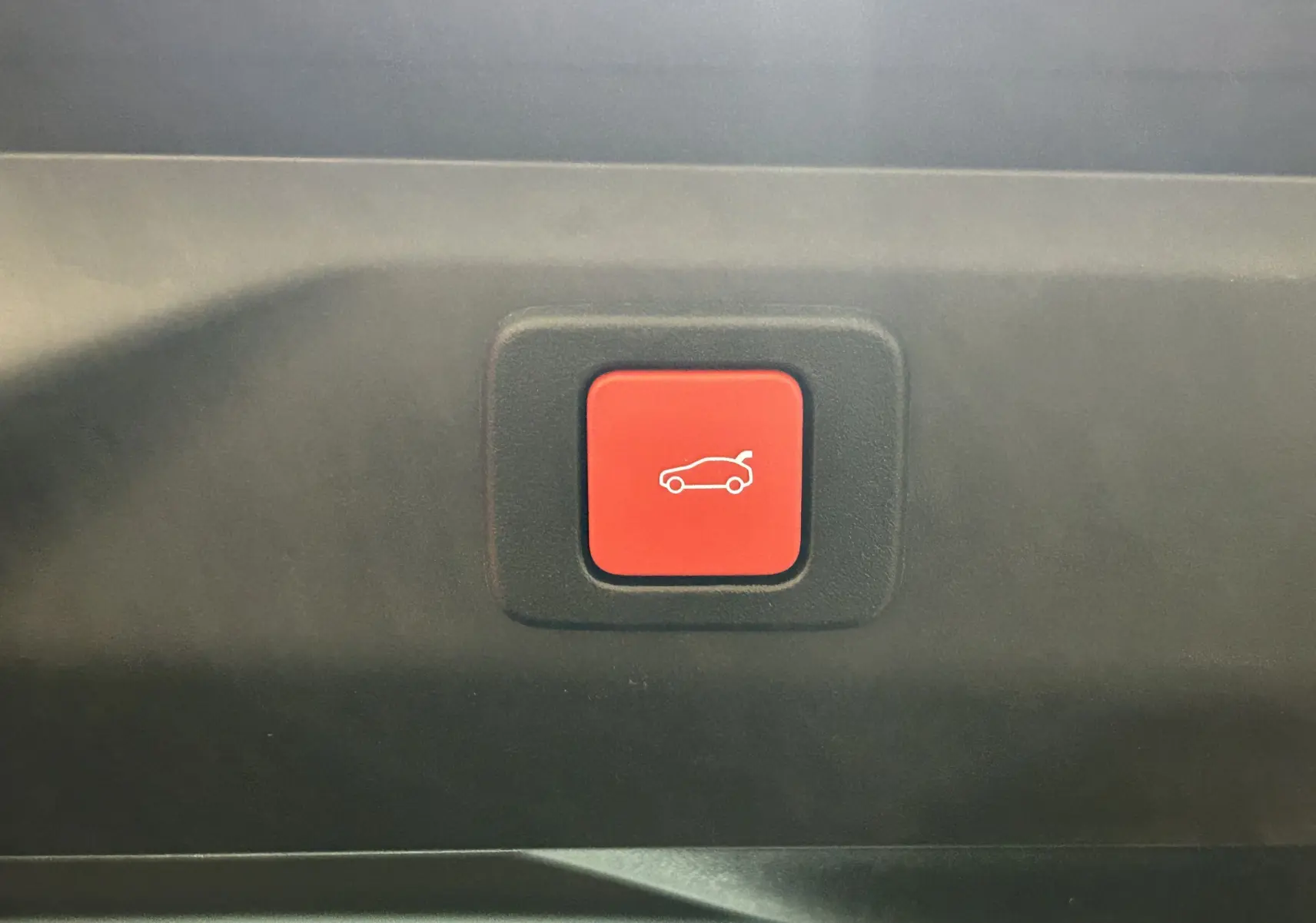 Bouton rouge intérieur du Peugeot 3008 Hybrid 2026, symbolisant l'ouverture électrique du hayon arrière.