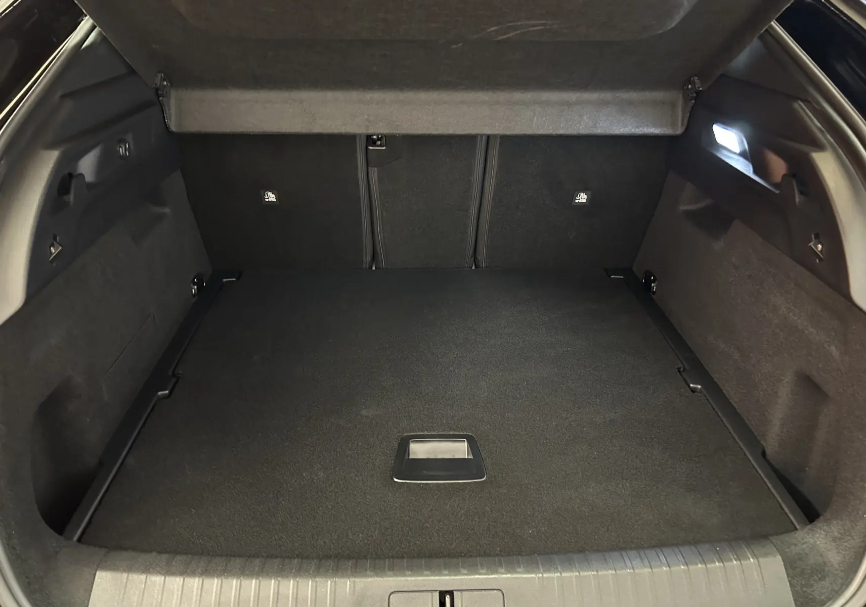 Coffre ouvert vu de l'arrière d'un Peugeot 3008 blanc, montrant un espace de chargement propre et éclairé.