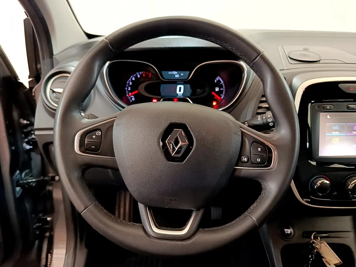 Intérieur du Renault Captur Business gris foncé, vue centrée sur le volant cuir multifonctions et le tableau de bord numérique.