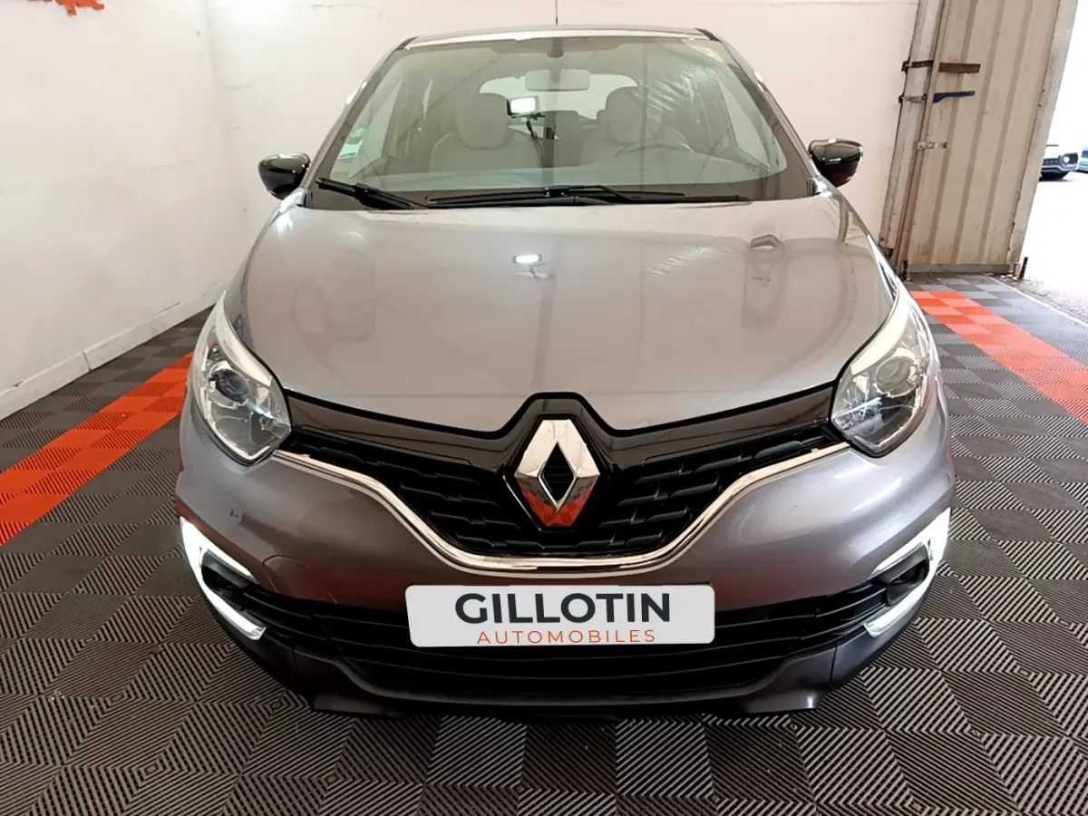 Vue frontale d'une Renault Captur gris foncé avec feux diurnes LED allumés et logo marqué au centre de la calandre.