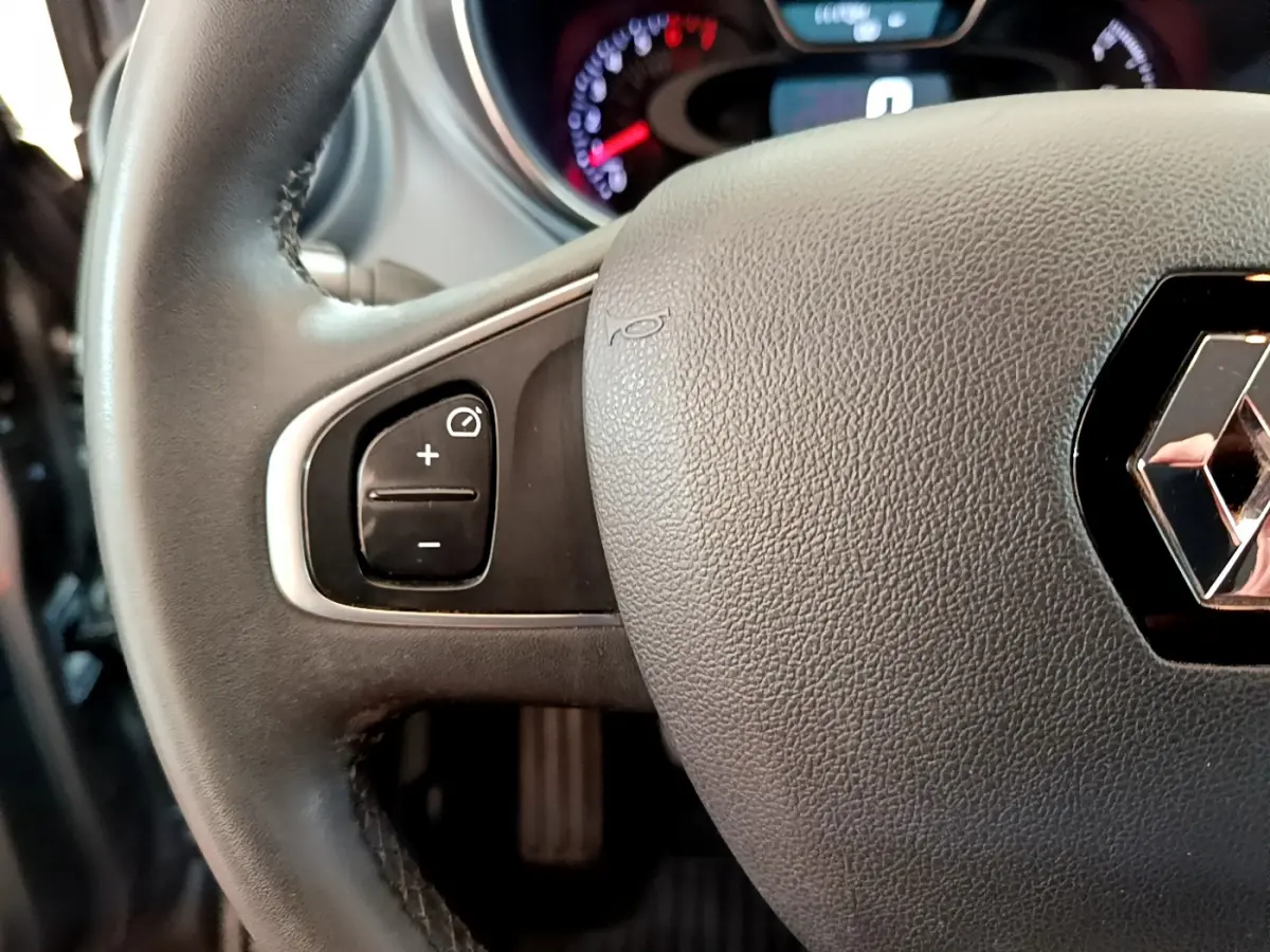 Gros plan sur le volant cuir gris du Renault Captur Business, avec commandes de régulateur de vitesse visibles à gauche.