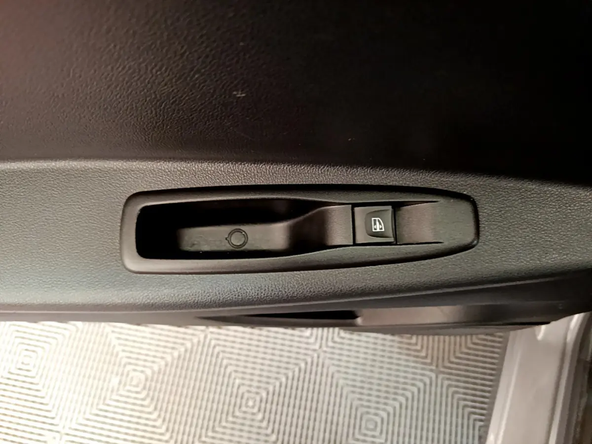 Bouton de commande électrique de la vitre sur la portière intérieure d'un Renault Captur gris foncé, vue rapprochée.