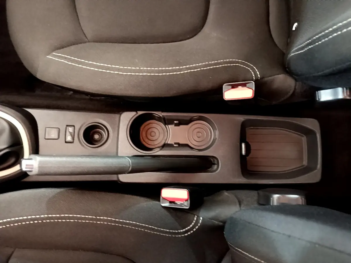 Vue plongeante sur la console centrale noire du Renault Captur gris foncé, avec frein à main manuel et porte-gobelets.