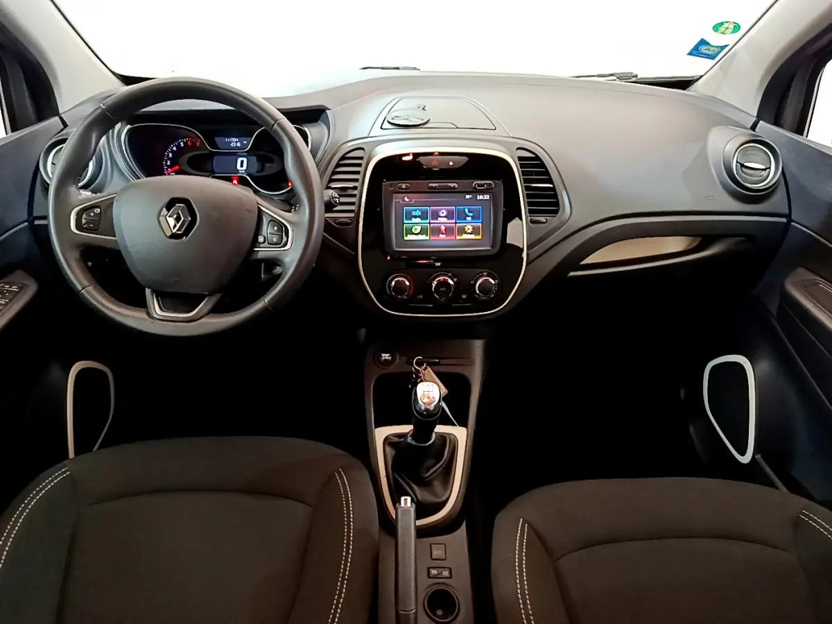 Vue intérieure frontale du tableau de bord du Renault Captur Business gris foncé avec écran tactile et volant cuir multifonctions.