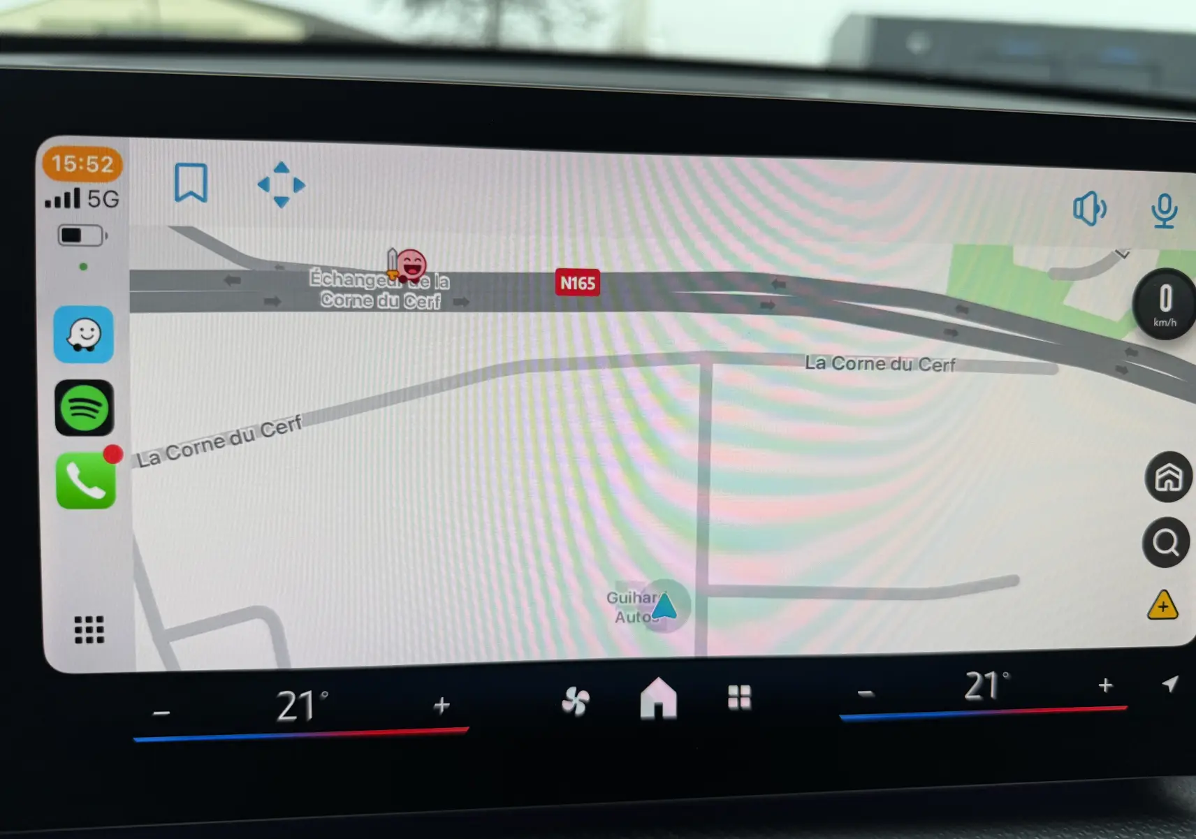 Écran de navigation intérieur d'un BMW X1 blanc minéral, affichant une carte routière avec commandes climatisation à 21°C.