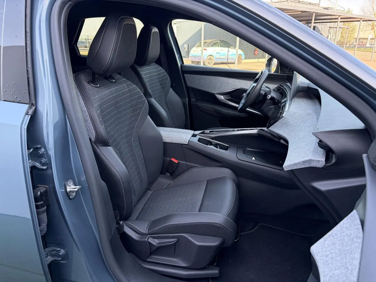 Vue intérieure côté conducteur du Peugeot 3008 bleu Ingaro 2024, sièges tissus et cuir avec tableau de bord gris clair.