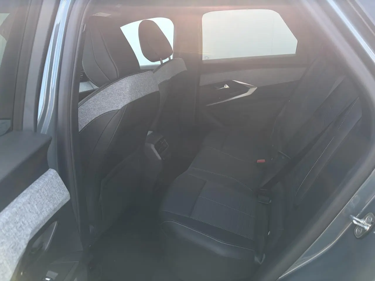 Vue intérieure côté gauche des sièges arrière noirs avec surpiqûres blanches du Peugeot 3008 bleu Ingaro 2024.