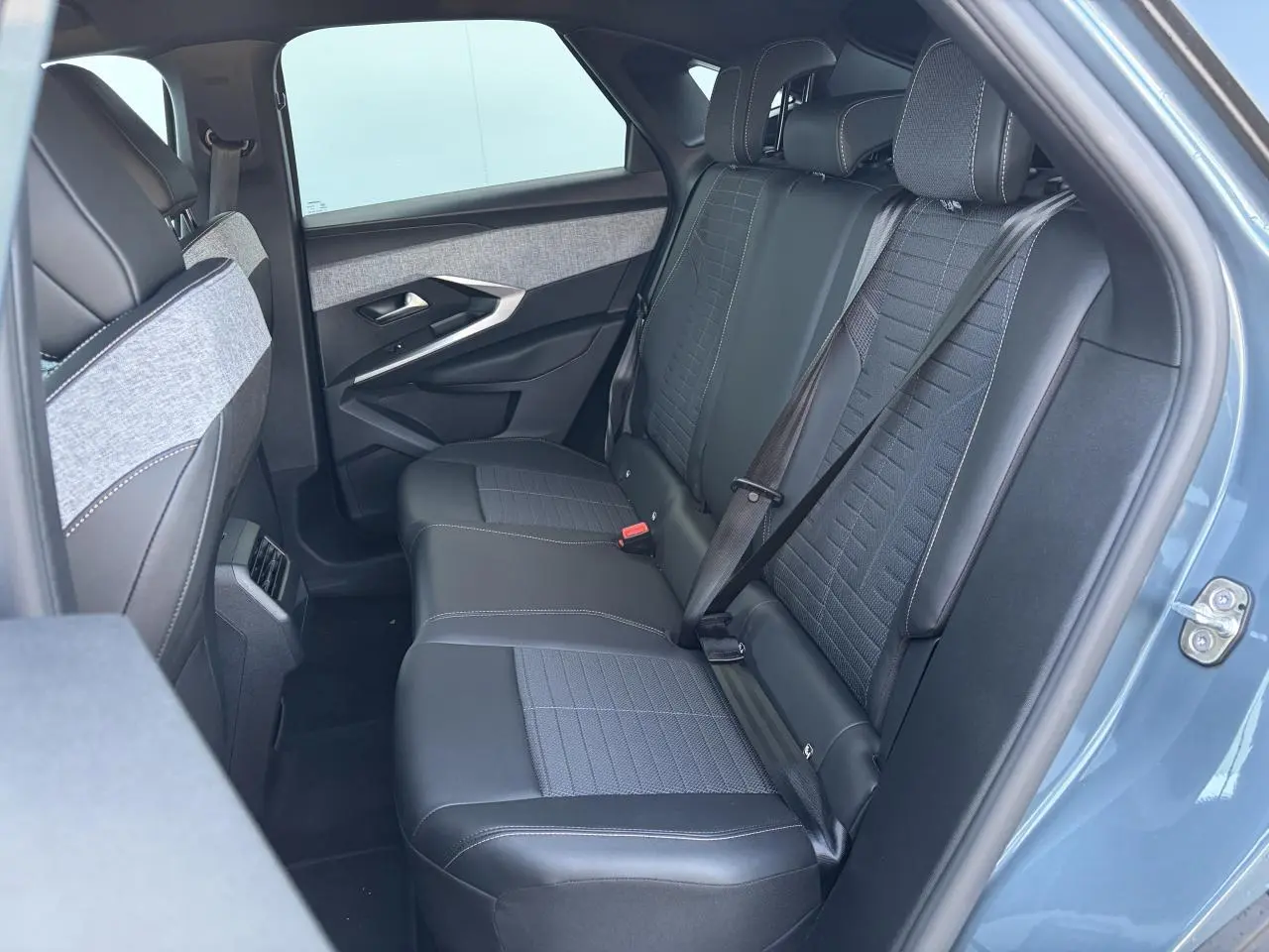 Vue intérieure arrière côté droit du Peugeot 3008 bleu Ingara, sièges tissu et cuir avec ceintures attachées.