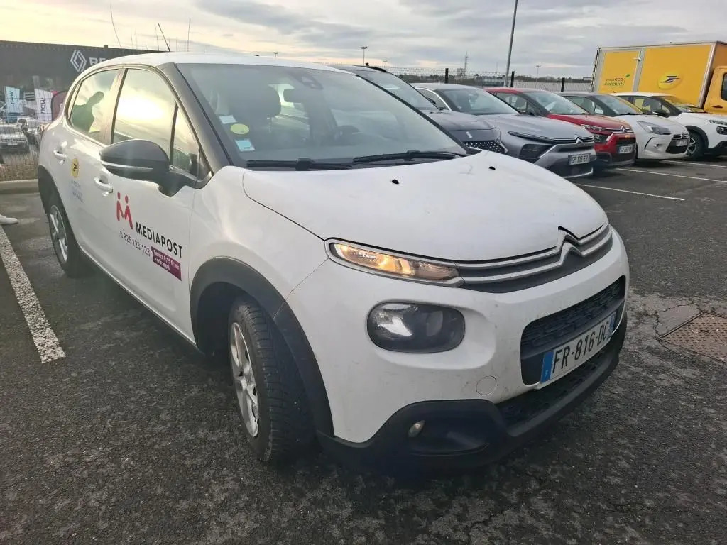 Vue 3/4 avant gauche d'une Citroën C3 Société blanche avec logo Mediapost sur la porte, stationnée sur un parking.