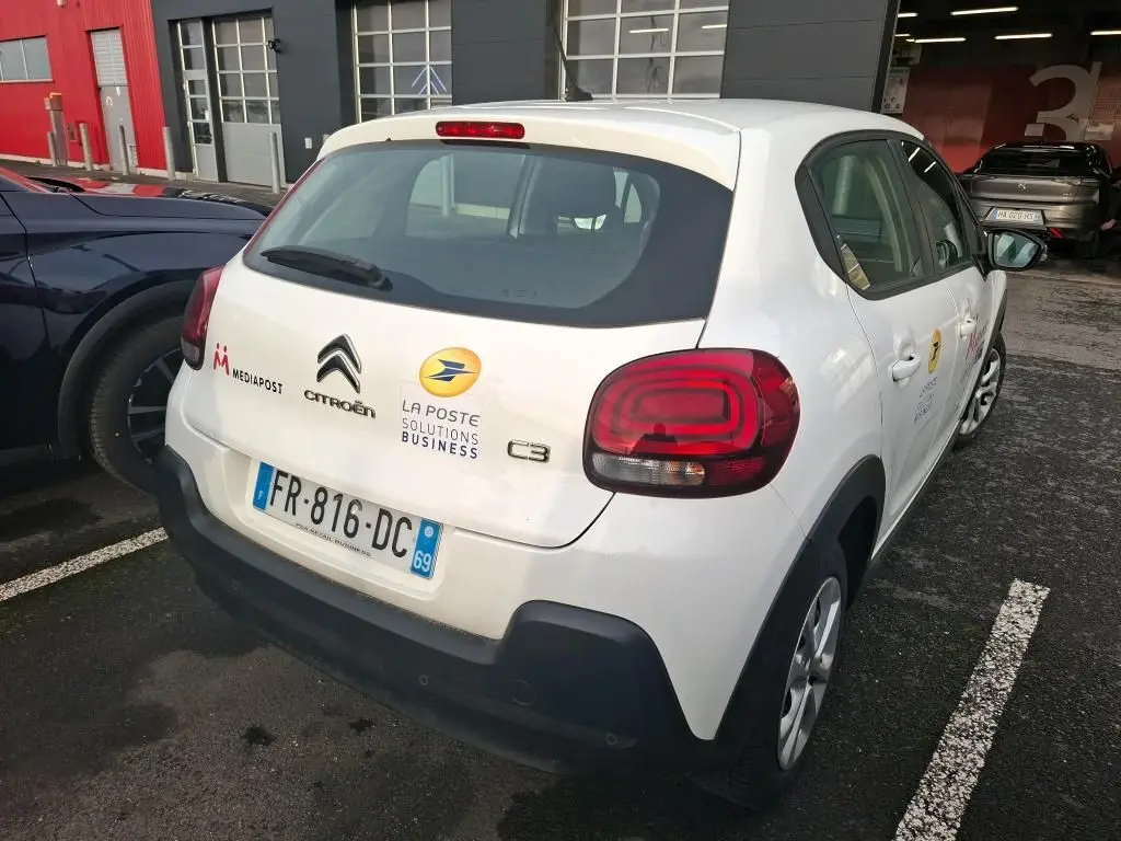 Vue 3/4 arrière droite d'une Citroën C3 blanche 2020 avec logos La Poste et Mediapost sur parking.
