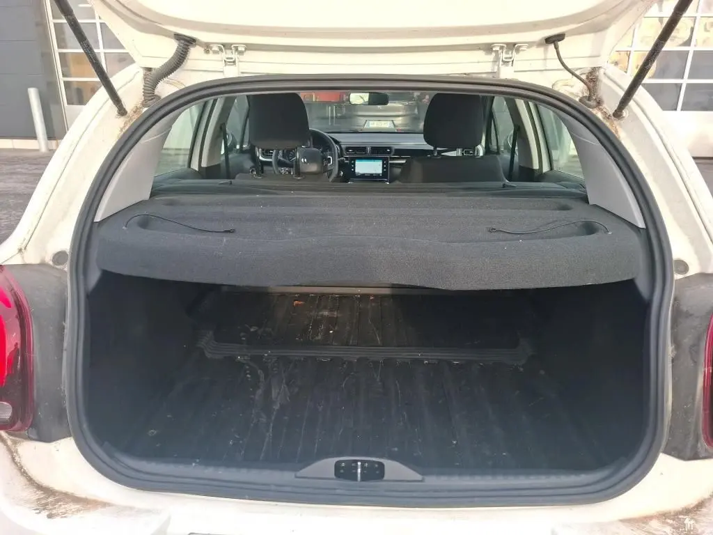 Vue arrière du coffre ouvert d'une Citroën C3 Société blanche, montrant l'intérieur spacieux et la tablette cache-bagages.