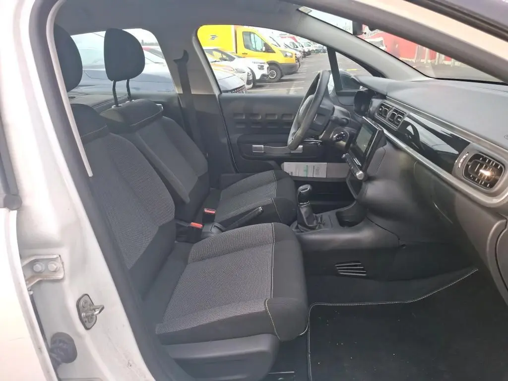Vue intérieure côté gauche de la Citroën C3 Société blanche, montrant les sièges avant et le tableau de bord avec écran tactile.