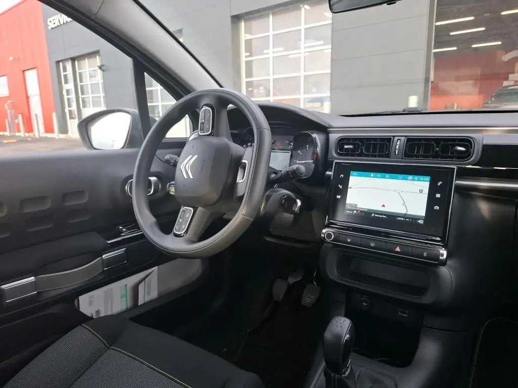 Vue intérieure côté conducteur de la Citroën C3 Société 2020, tableau de bord noir avec écran tactile et volant multifonction.