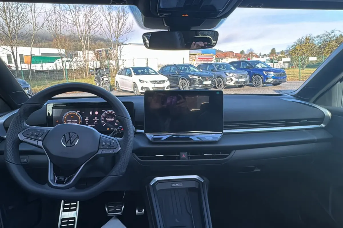 Vue intérieure frontale du tableau de bord noir du Volkswagen T-Roc 2026 avec volant multifonctions et écran tactile central.