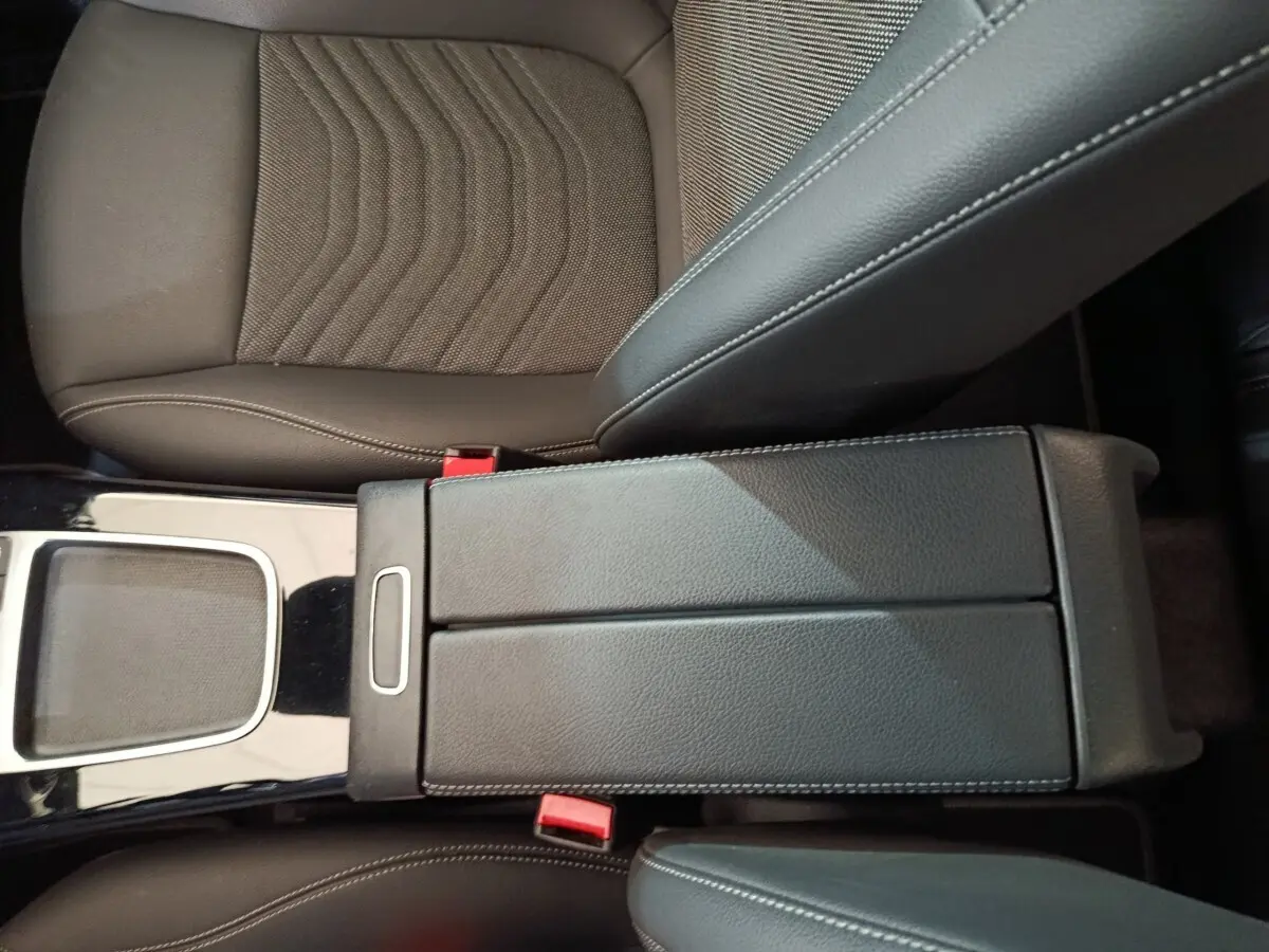 Vue rapprochée de l'accoudoir central en cuir noir et des sièges avant marron du Mercedes GLA 250 e Business Line 2023.
