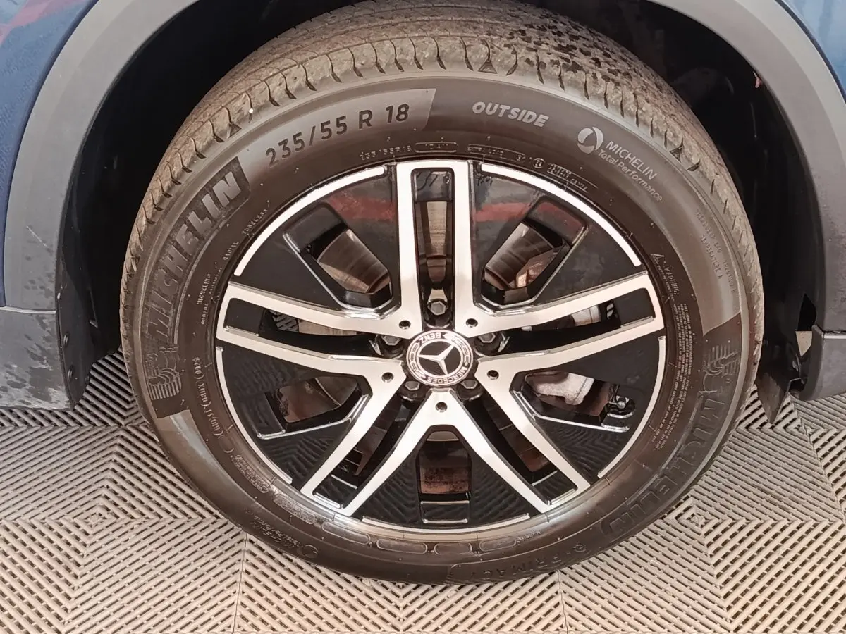Gros plan sur la roue avant droite avec jante alliage noir et argentée d'une Mercedes GLA 250 e gris foncé.