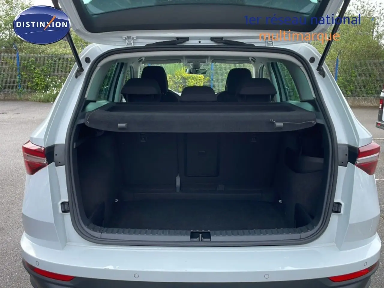 Vue arrière du coffre ouvert d'un Skoda Karoq blanc glacier 2025, montrant l'espace de chargement vide et la plage arrière.