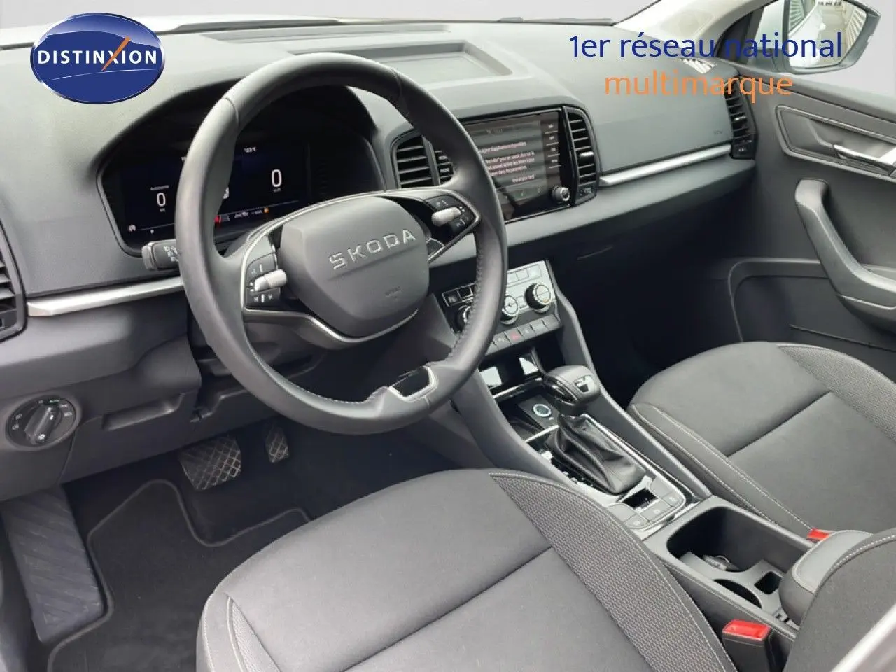 Vue intérieure côté conducteur du Skoda Karoq blanc glacier 2025, avec volant multifonction et console centrale moderne.