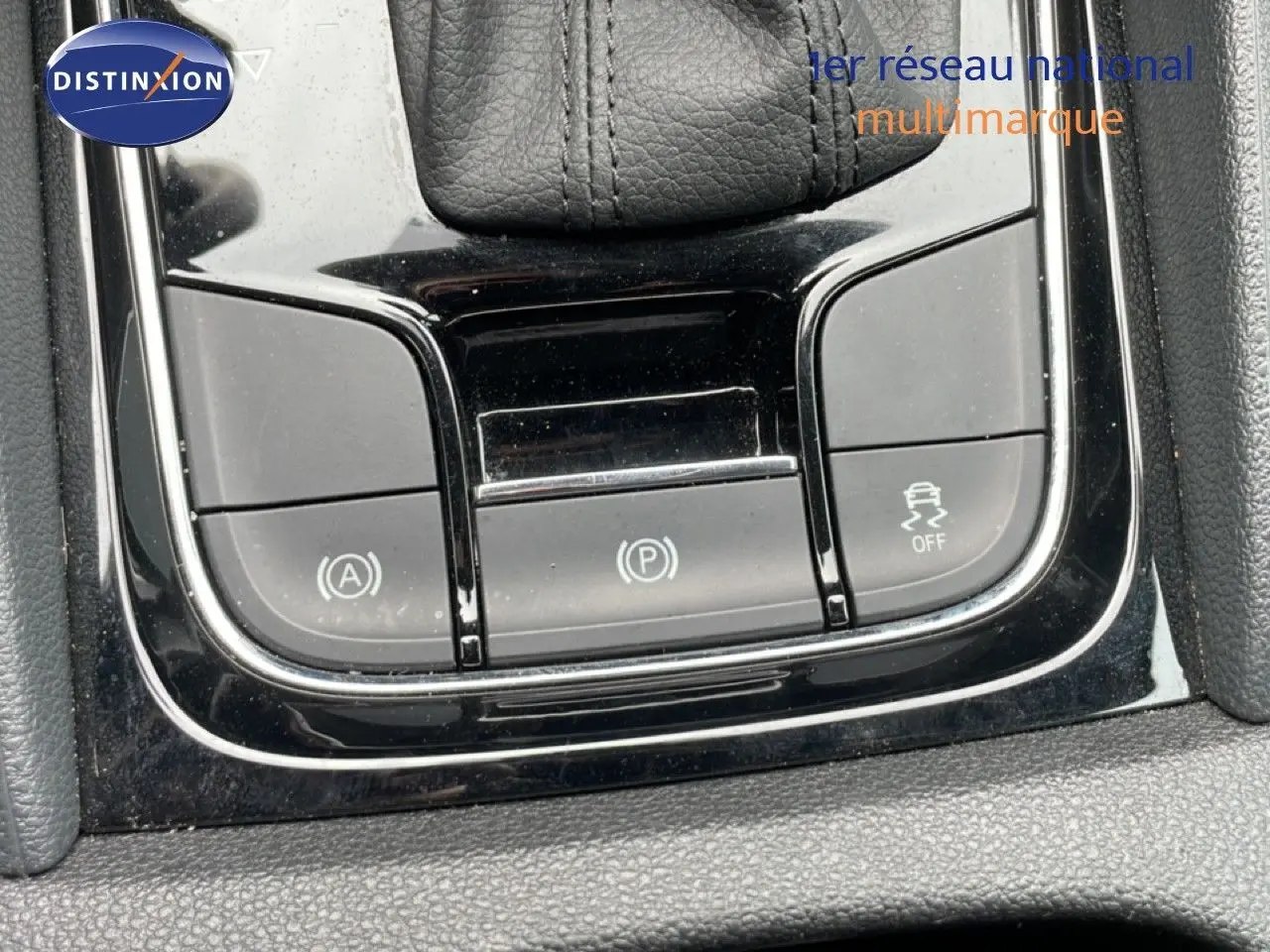 Gros plan sur la console centrale noire brillante du Skoda Karoq blanc glacier, montrant les boutons de contrôle électroniques.