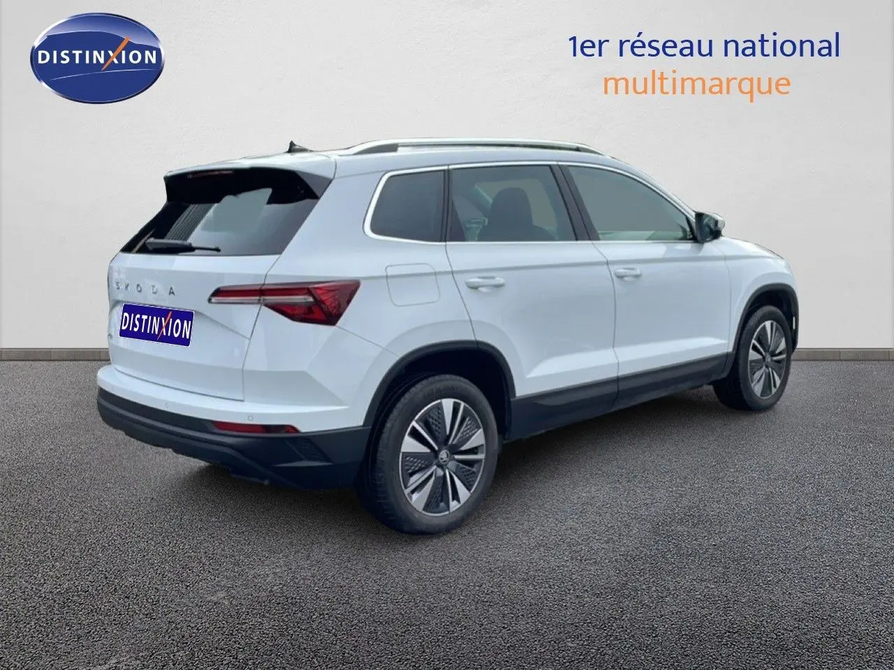 Vue 3/4 arrière droite d'un Skoda Karoq blanc glacier 2025 avec jantes bi-ton et toit noir contrasté.
