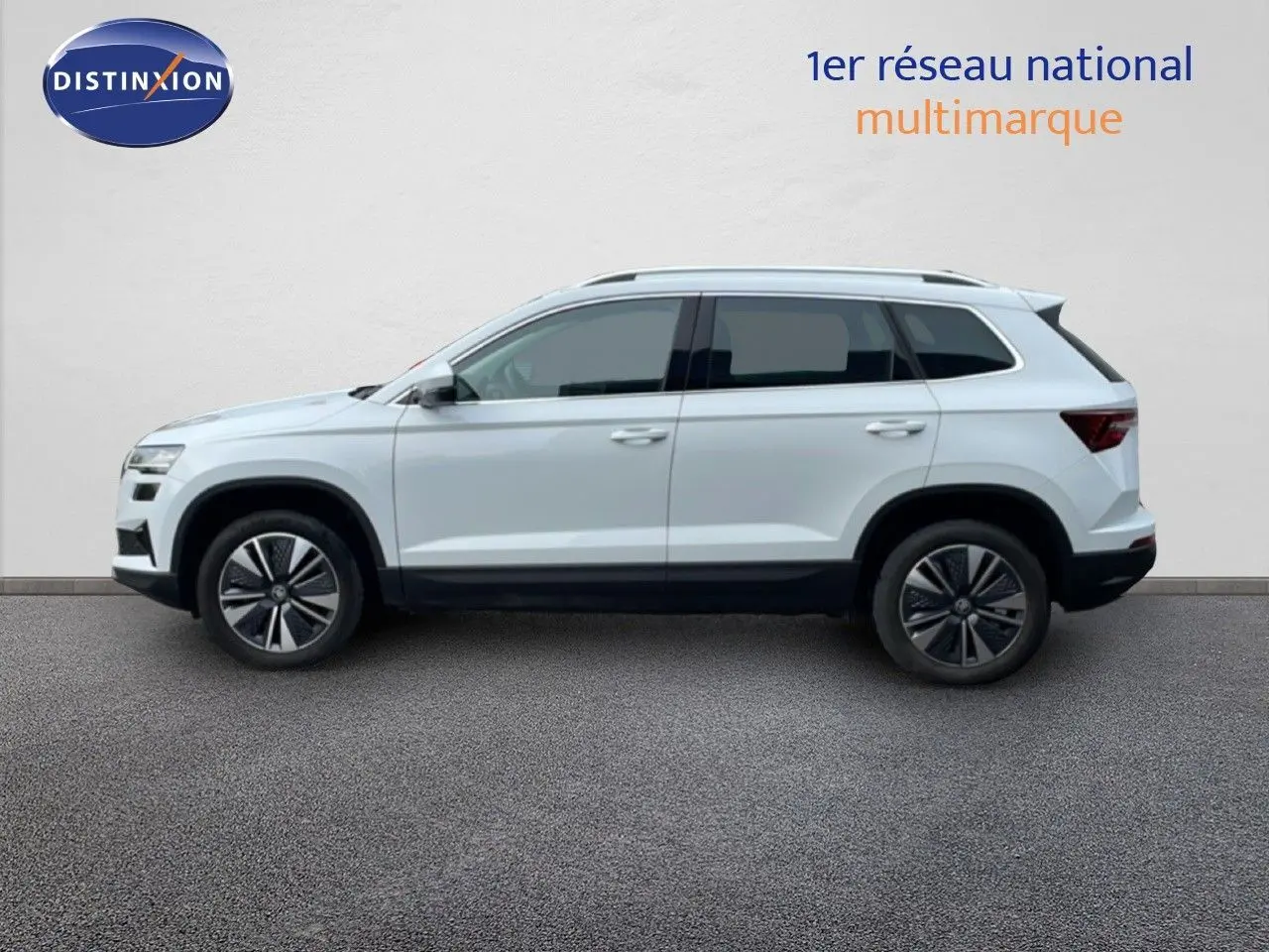 Profil droit d’un Skoda Karoq blanc glacier 2025 avec jantes alliage bicolores sur fond neutre.