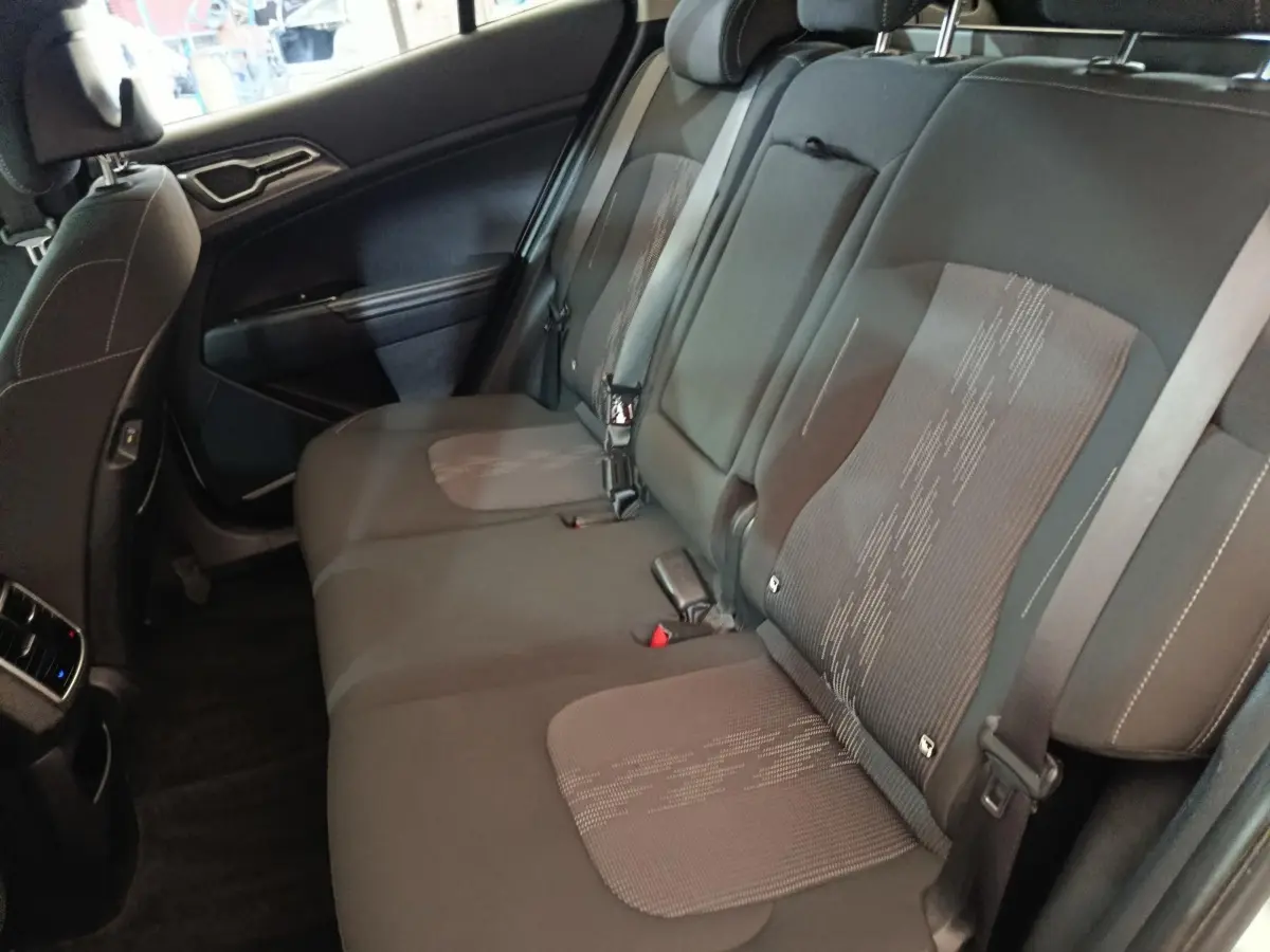 Vue intérieure côté gauche montrant la banquette arrière noire du Kia Sportage 2022 hybride rechargeable.