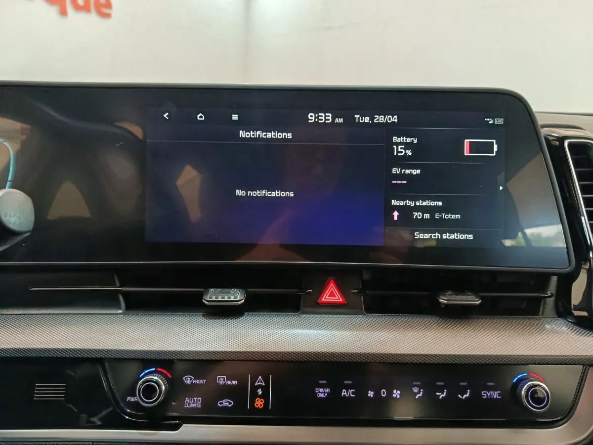 Vue rapprochée du tableau de bord numérique et de la console centrale du Kia Sportage blanc, affichage tactile et commandes climatisation.