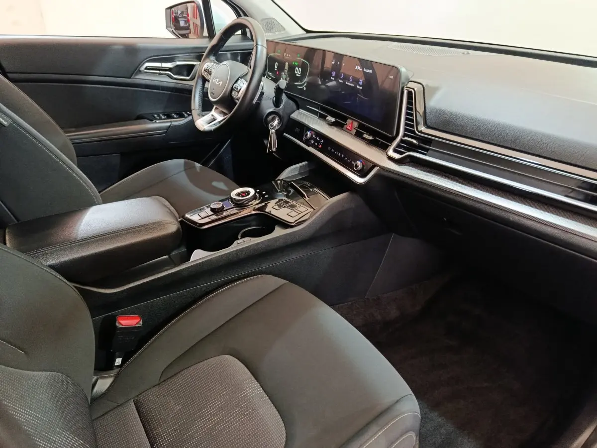 Vue intérieure côté conducteur du tableau de bord et console centrale du KIA SPORTAGE hybride rechargeable 2022, finition noire.