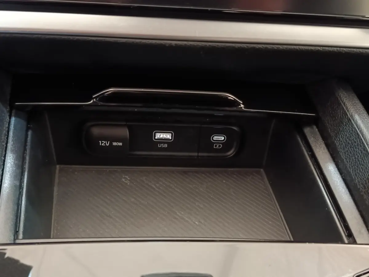 Gros plan sur la console centrale noire du Kia Sportage 2022 avec prises USB et 12V visibles.