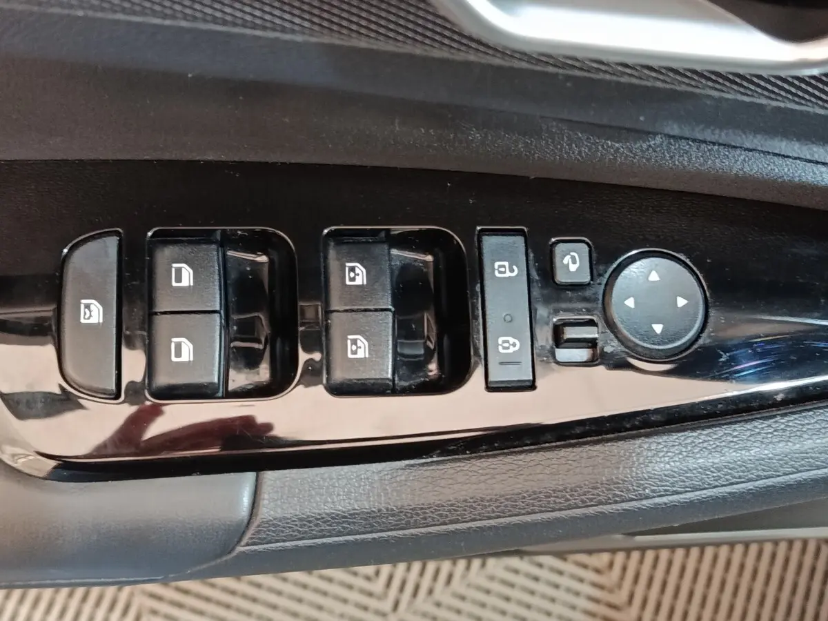 Gros plan sur les commandes de lève-vitres et rétroviseurs côté conducteur du Kia Sportage blanc 2022.