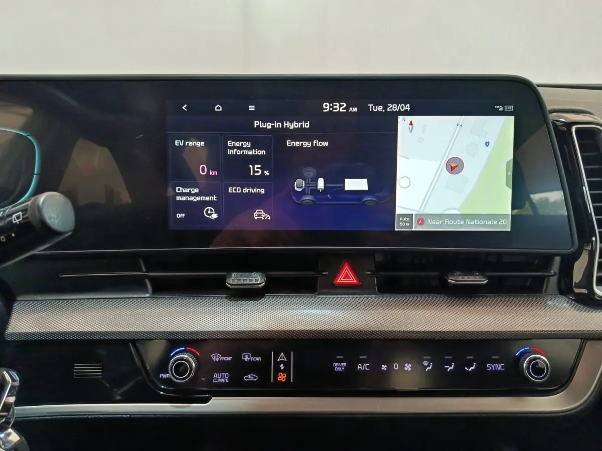 Vue rapprochée du tableau de bord numérique du Kia Sportage hybride rechargeable 2022 avec écran tactile affichant navigation et données énergie.