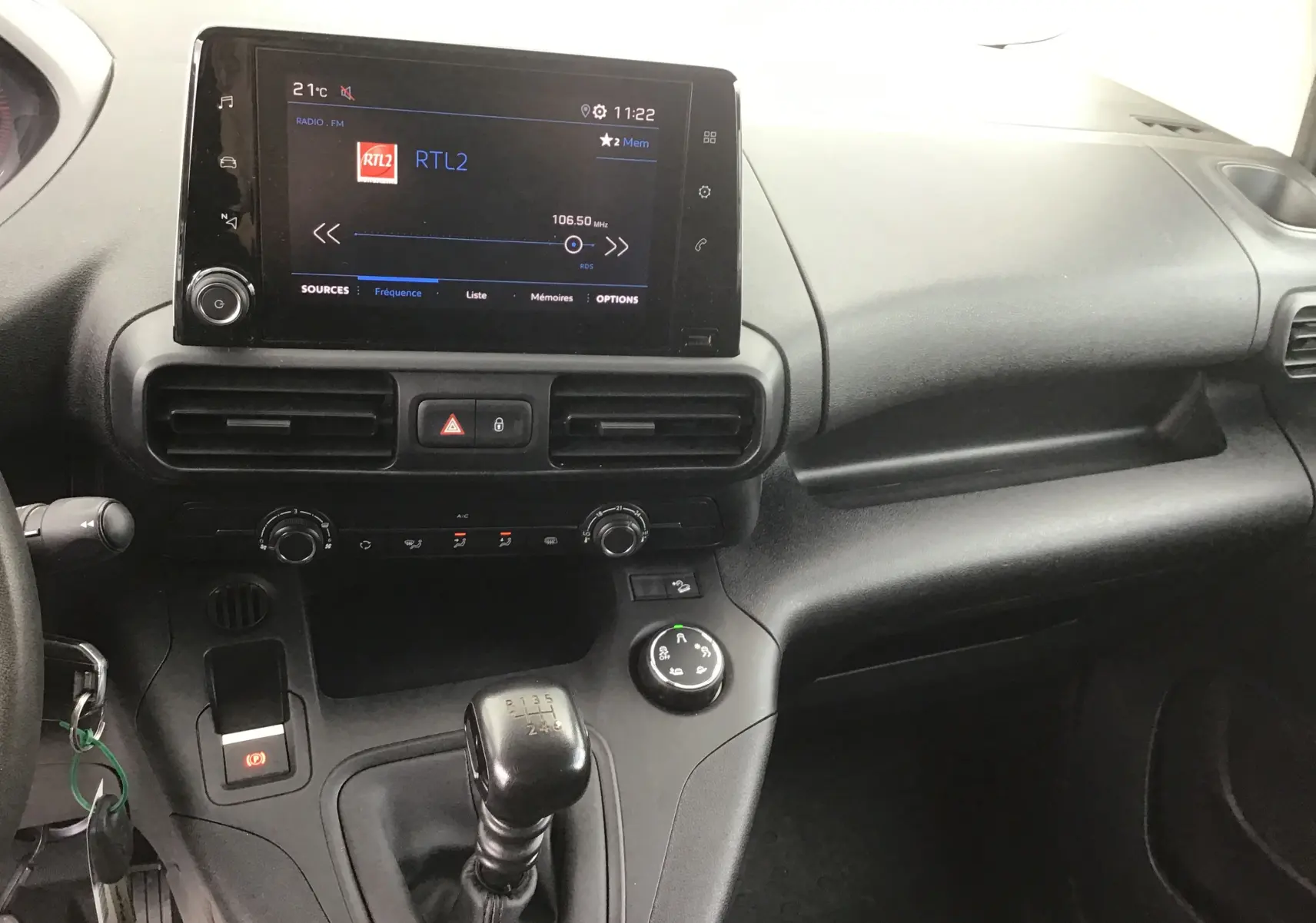 Vue intérieure du tableau de bord du Peugeot Partner blanc 2022, avec écran tactile central et levier de vitesse manuel.
