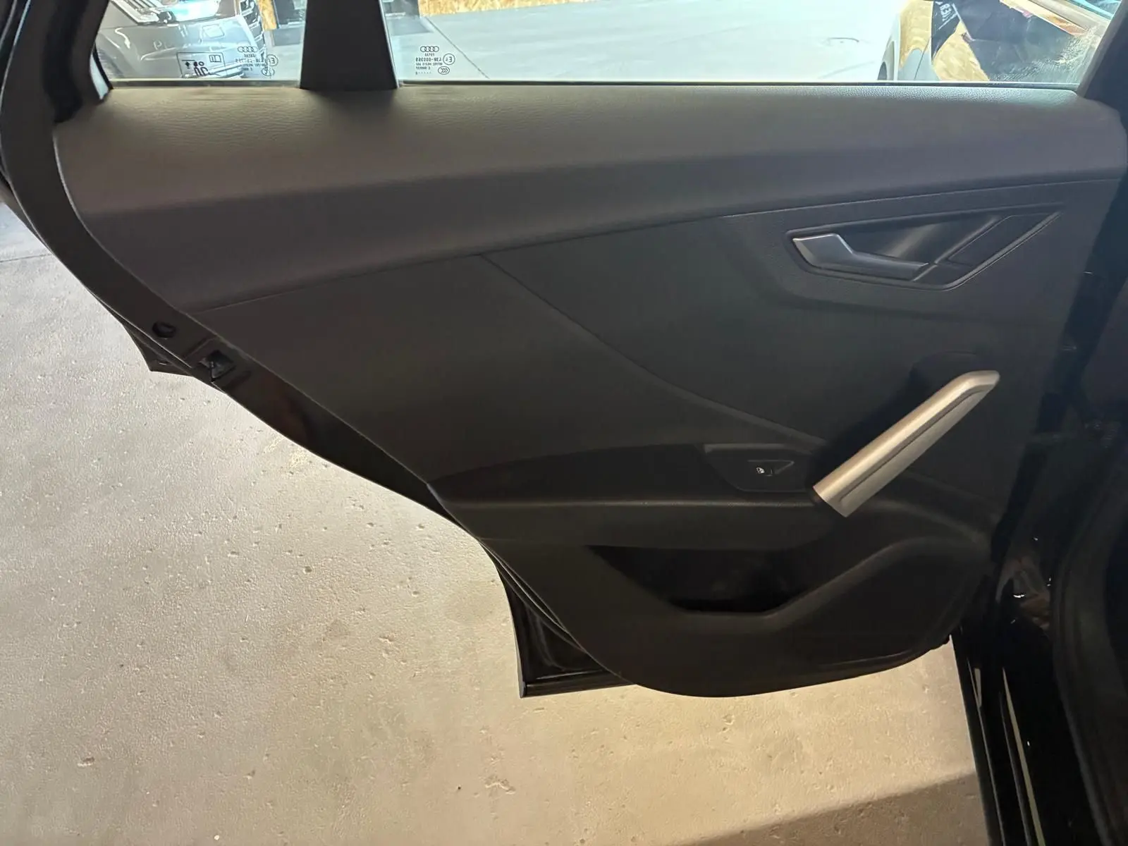 Vue intérieure de la porte arrière droite noire d'un Audi Q2 2020, avec poignée argentée et commande de fenêtre.