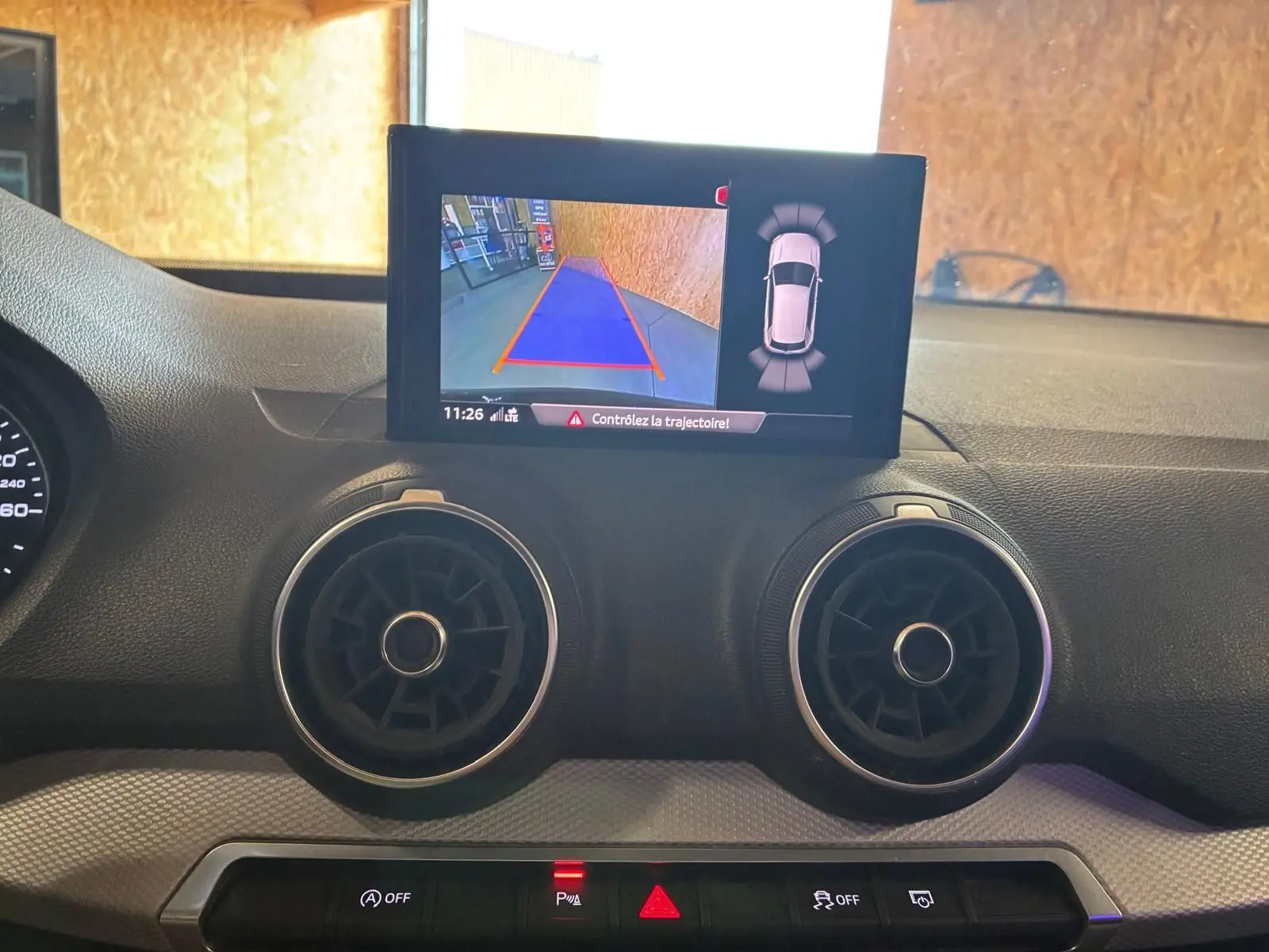 Vue intérieure du tableau de bord de l'Audi Q2 2020 noir, avec écran de caméra de recul et aérateurs ronds.