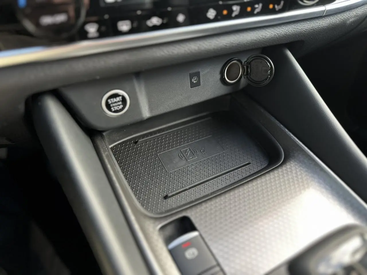 Gros plan sur la console centrale noire du Nissan Qashqai 2025 avec bouton start/stop et chargeur à induction.