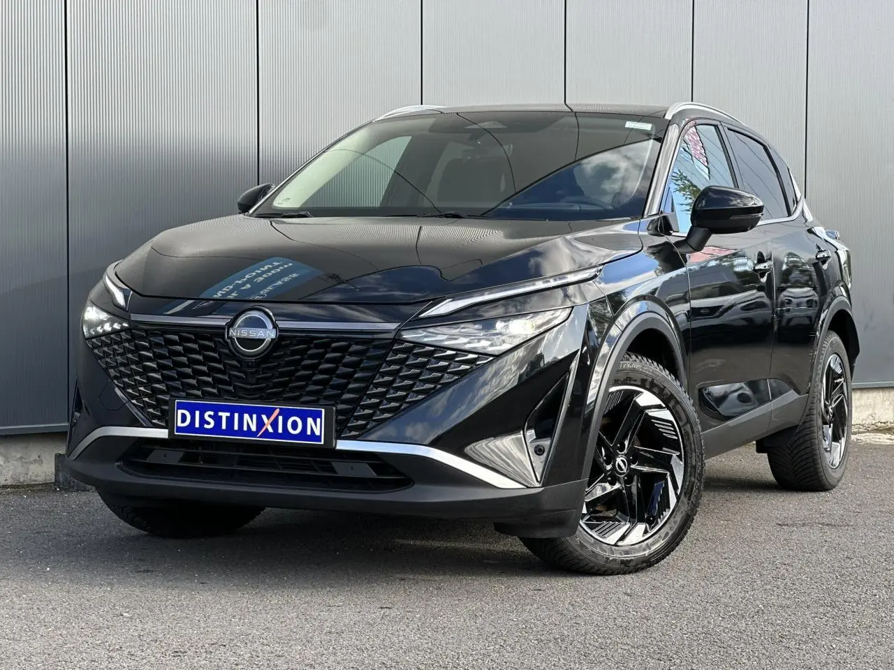 Nissan Qashqai 2025 noir nacré en 3/4 avant droit, avec calandre distinctive et jantes alliage noires.
