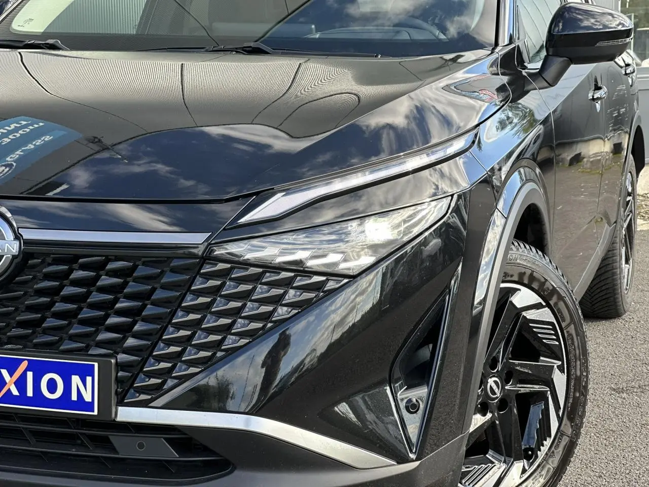 Vue 3/4 avant droit du Nissan Qashqai noir nacré avec calandre distinctive et jantes alliage 18 pouces.