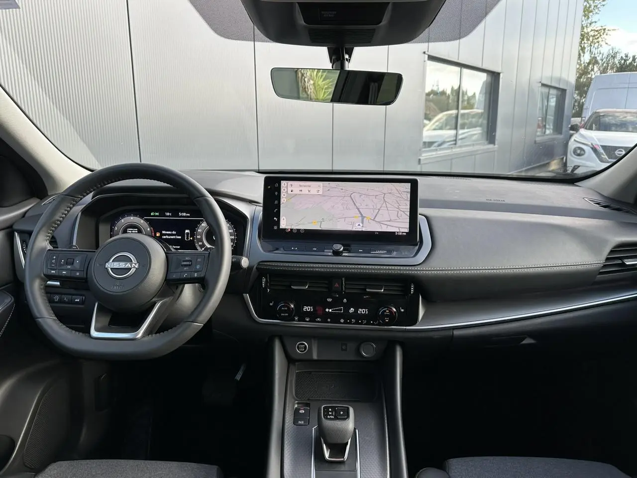 Vue intérieure avant du Nissan Qashqai 2025 noir nacré, tableau de bord moderne avec écran tactile et volant cuir.