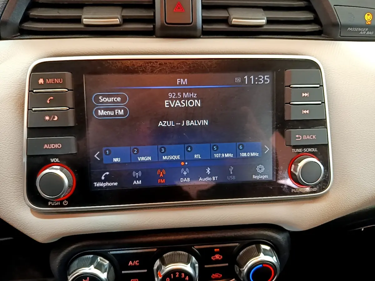 Écran tactile central allumé de la Nissan Micra blanche 2022, affichant la radio FM et commandes audio.