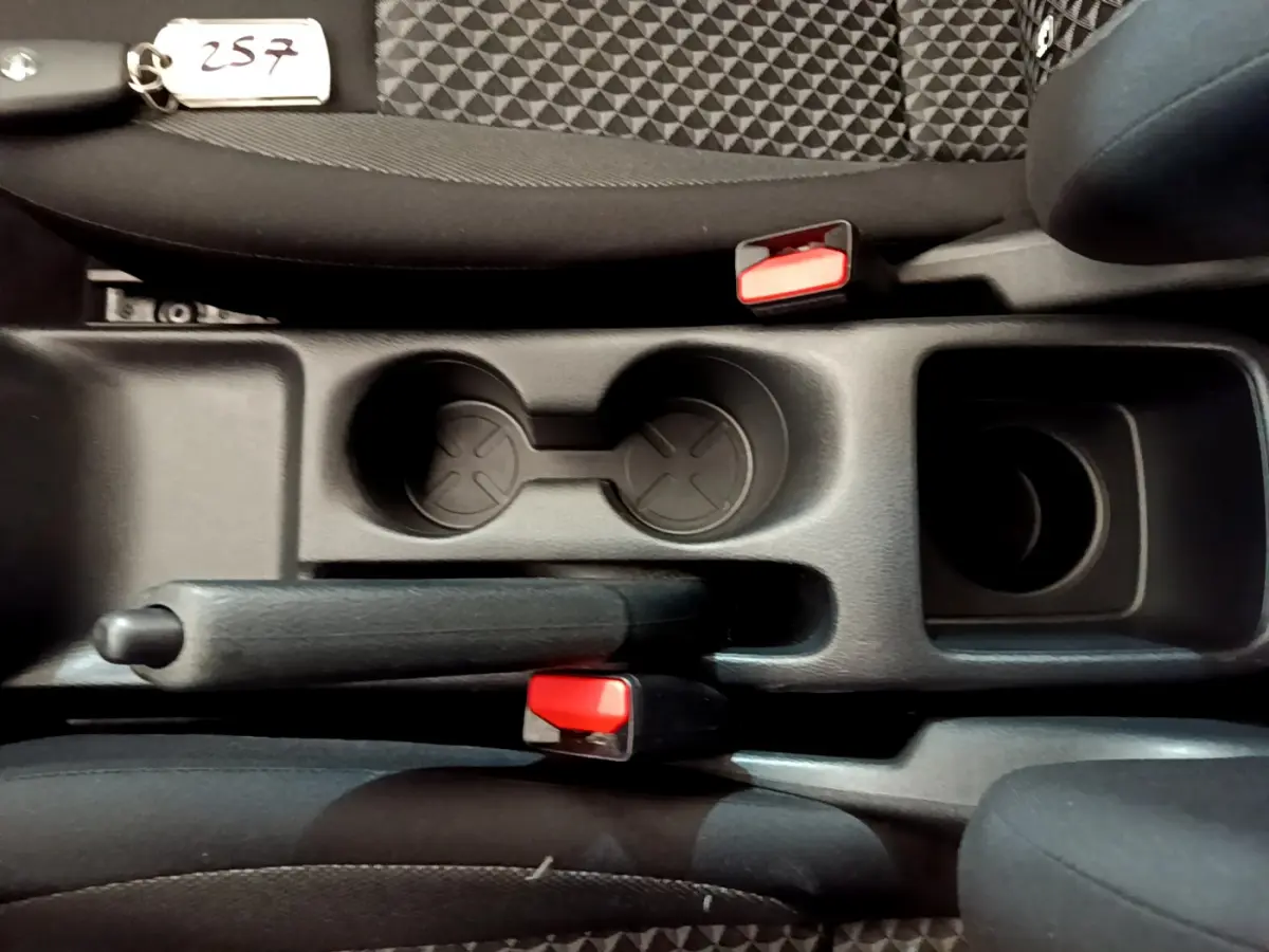 Vue plongeante sur la console centrale noire de la Nissan Micra Acenta 2022, montrant frein à main et porte-gobelets.