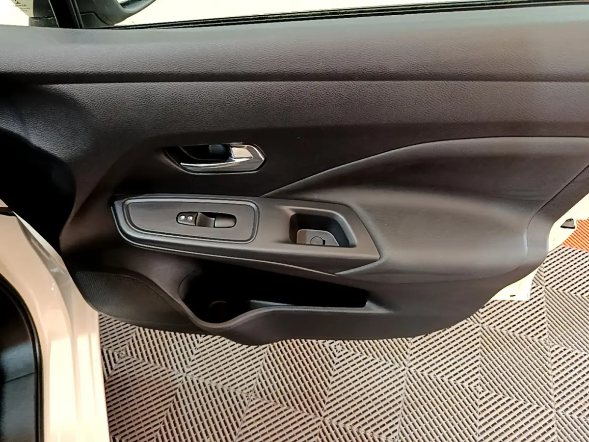 Vue rapprochée de la porte avant gauche noire de la Nissan Micra blanche 2022, avec commandes de vitres et poignée chrome.